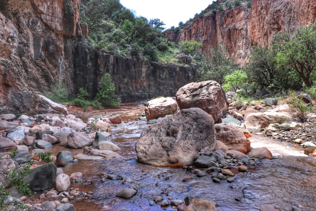 Big boulders and smaller rocks in the shallow water below Cibecue Falls