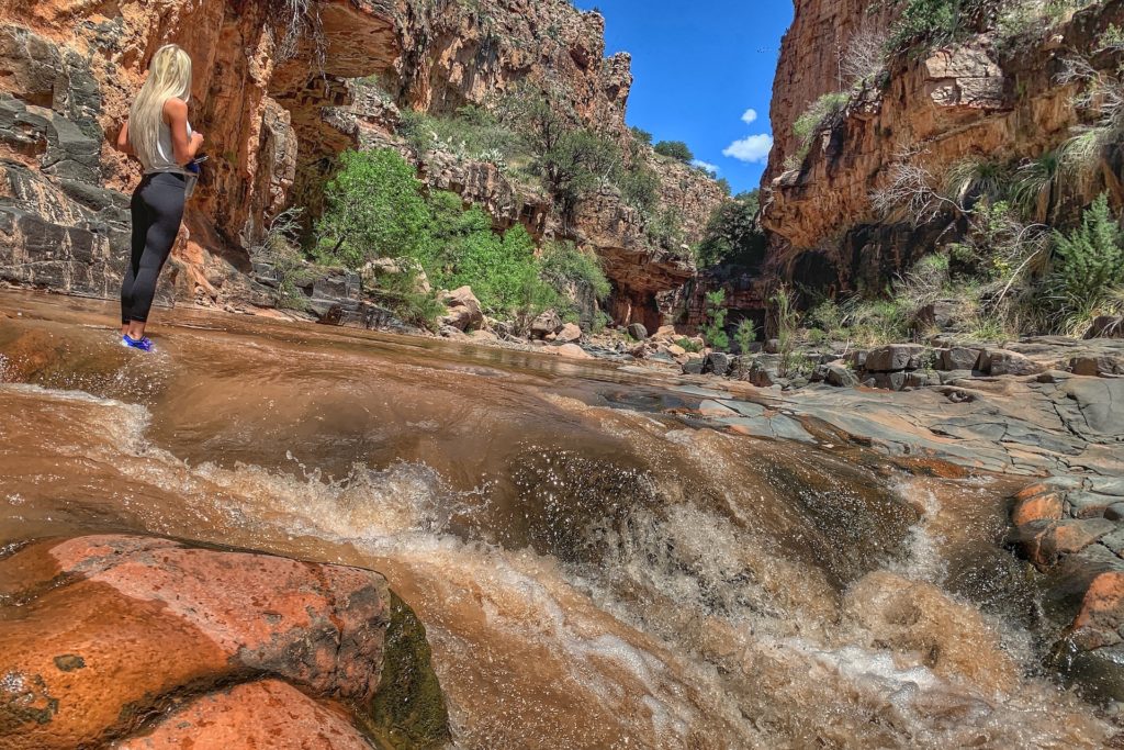 Woman standing in the shallow Cibecue falls waterhole while on a hike.