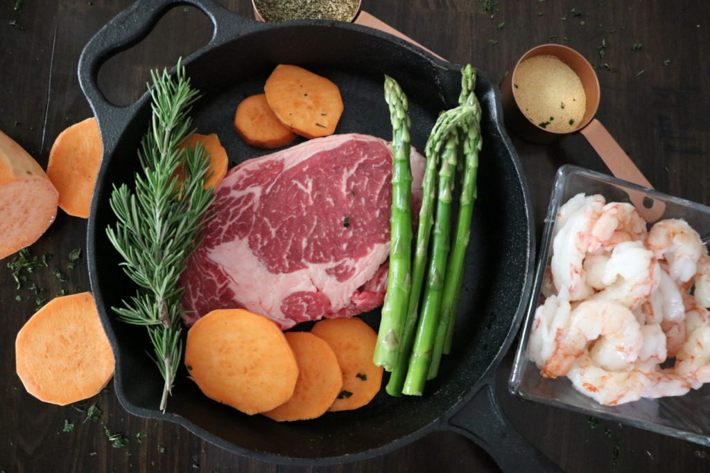 Displays steak, sweet potatoes and asparagus in a skillet with uncooked shrimp in a glass bowl beside it. This is a dish you would use the Quick & Tasty Asparagus Recipe